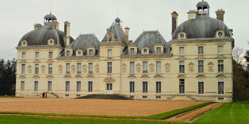 Château de Cheverny, a grand 17th-century French château with symmetrical architecture, elegant domed towers, and intricate detailing, set against a gravel courtyard and green lawns.