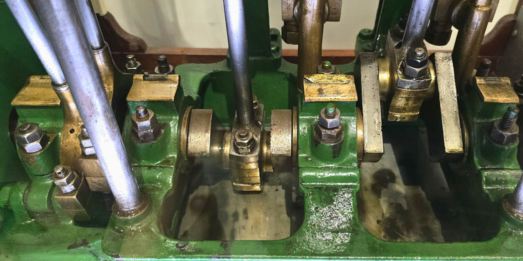 A close-up of a vintage steam engine's mechanical components, including pistons, connecting rods, and bearings.