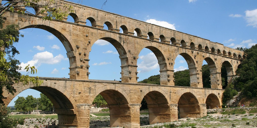 An ancient Roman aqueduct with multiple tiers of arches spanning a river.