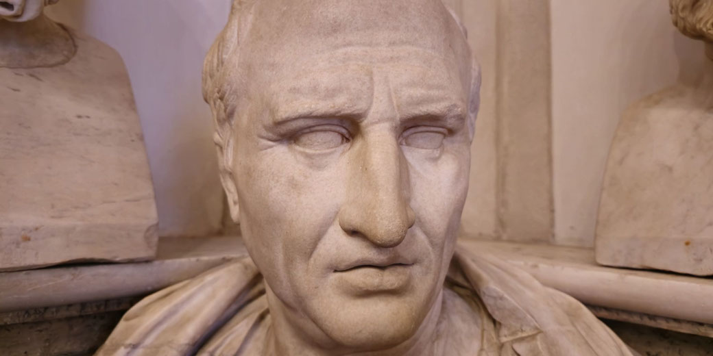 Marble bust of a stern-looking man with a furrowed brow and draped clothing.