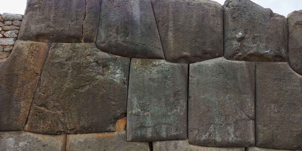 Incan masonry with massive, precisely cut stone blocks fitted seamlessly without mortar, demonstrating the advanced engineering skills of the Inca civilization.