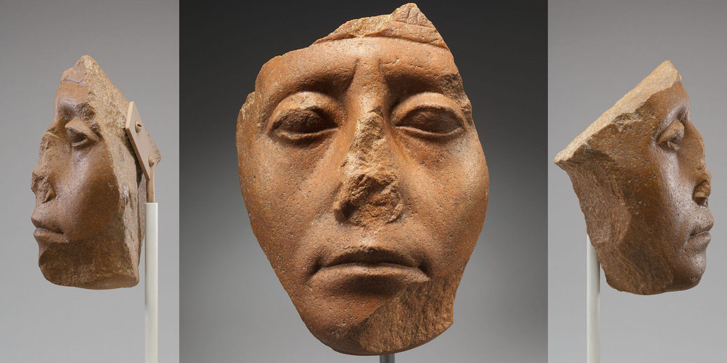 Fragment of a red quartzite statue depicting Senwosret III with deep-set eyes, thin lips, and furrowed cheeks, conveying a contemplative expression.