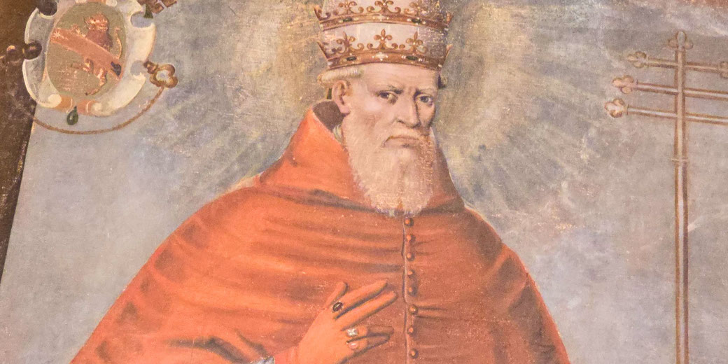 Medieval painting of a pope with a triple tiara and red robes, raising his right hand in a gesture of blessing, set against a faded, radiant background.