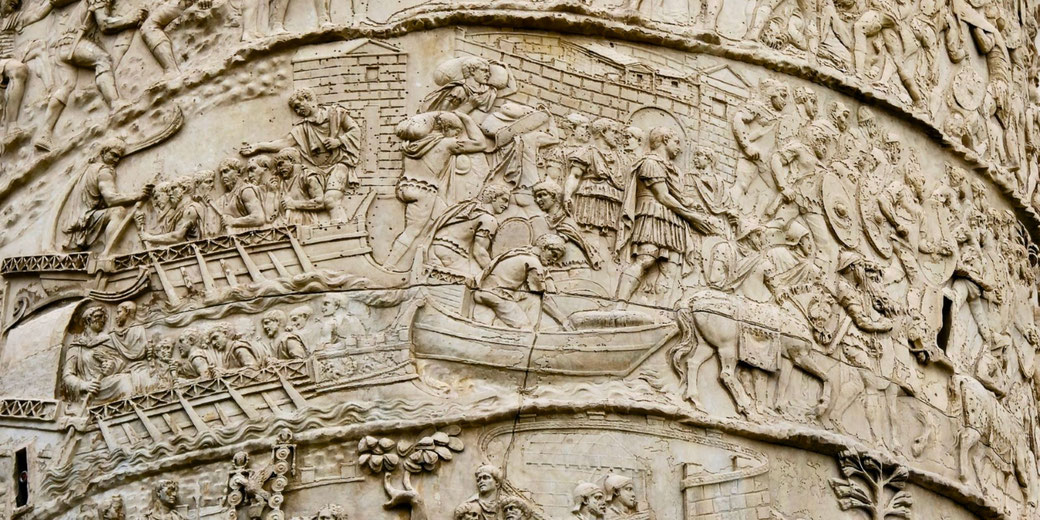Detailed Roman column relief depicts scenes of soldiers crossing a river, building, and marching in battle formation.