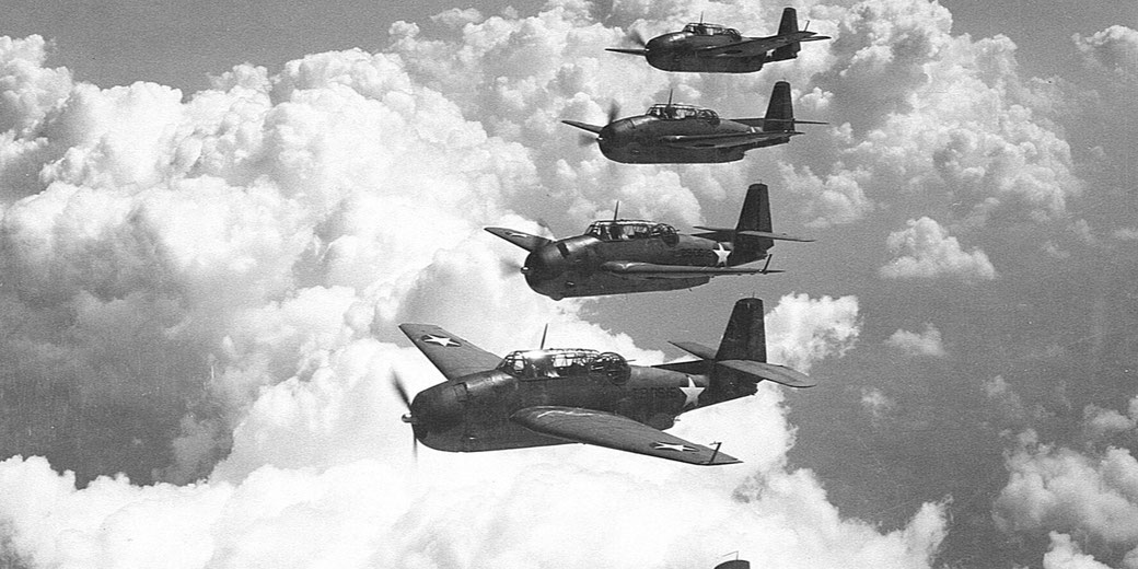 A formation of U.S. WWII fighter planes flies above the clouds during a military mission.