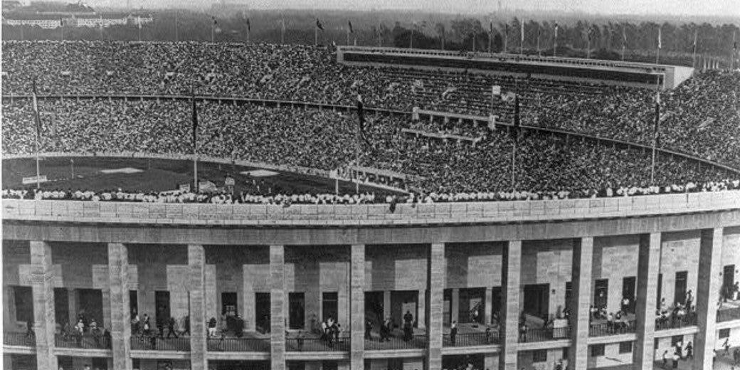 A packed stadium with thousands of spectators filling every tier, likely during a major event or competition, viewed in black and white.
