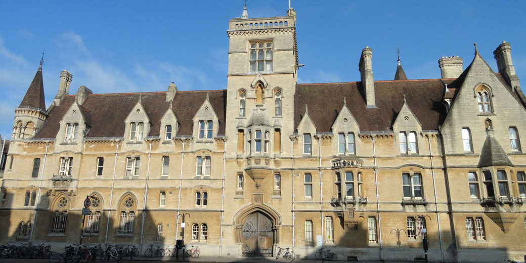 A historic Gothic-style building with pointed roofs, arched windows, and a central tower. The architecture suggests it is part of a university in Oxford, UK.