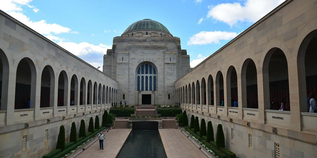 The Australian War Memorial features a domed hall with arched colonnades and a long reflecting pool.