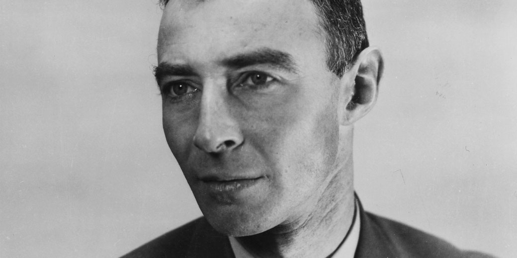 Black and white close-up portrait of a man with a serious expression, short dark hair, and wearing a suit jacket and collared shirt.