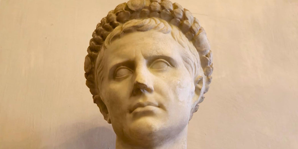 Marble bust of a youthful man with short hair and a laurel wreath, symbolizing victory or imperial status.