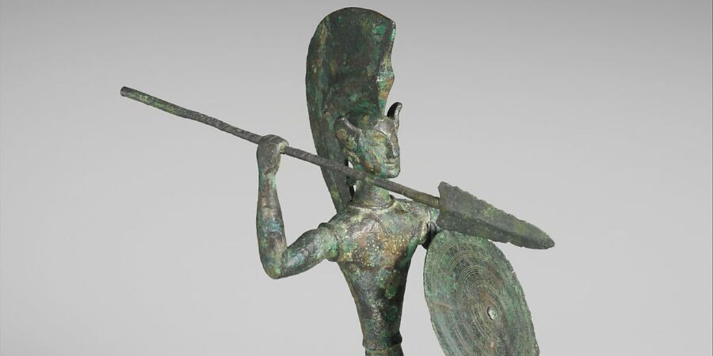 Etruscan bronze figure from Populonia, featuring a warrior with spear and shield adorned with concentric bands and zigzags.