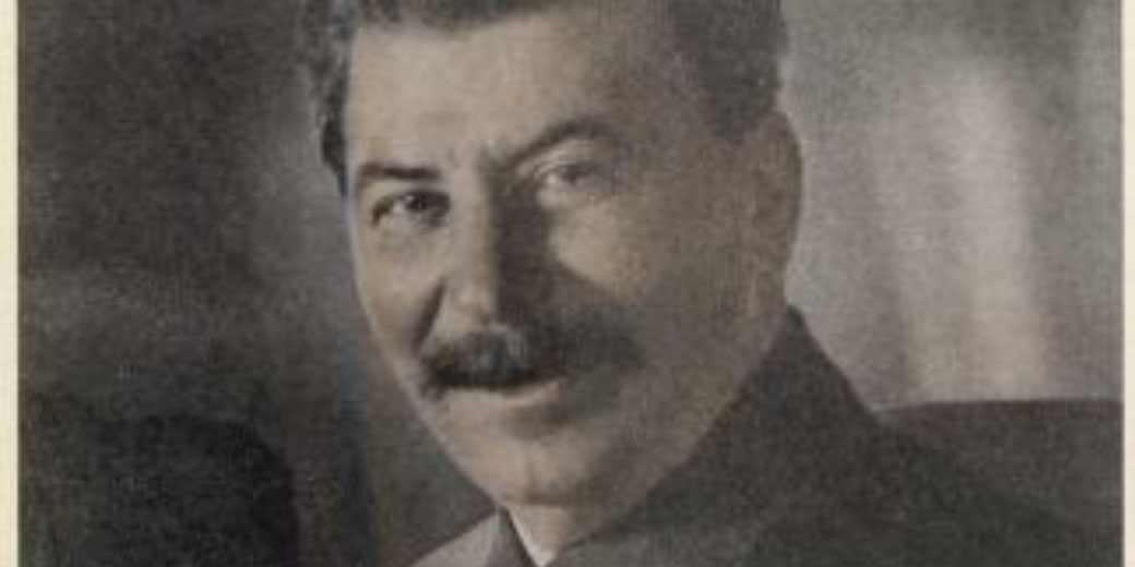 A man with a mustache in formal attire faces the camera with a faint smile in a vintage portrait.