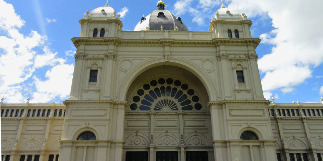 The Royal Exhibition Building in Melbourne, Australia. It features grand arches, intricate detailing, and a large central dome, exemplifying 19th-century Victorian architecture.