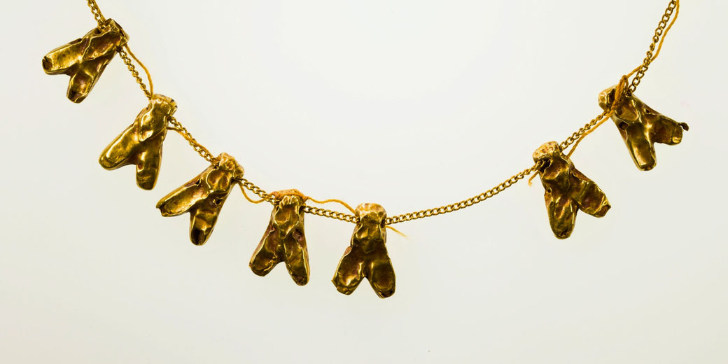Ancient gold necklace with multiple bee-shaped pendants hanging from a fine chain, displayed against a plain light background.