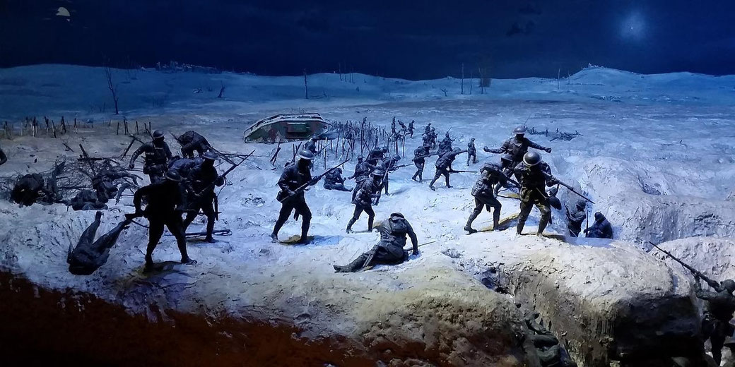 Diorama of World War I soldiers in battle, advancing through snowy trenches with rifles; a tank and barbed wire are visible in the background under a dark sky.