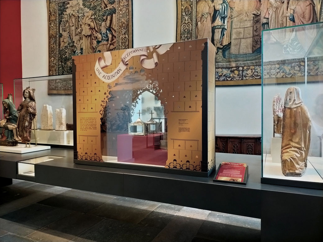 Conception du décor de la vitrine. Faux doré avec motif trilobé ajouré en façade. A l'intérieur, des scènes historiques illustre le contexte et un adhésif miroir découpé permet d'admirer l'arrière du reliquaire. Parcours permanent, musée Crozatier. 