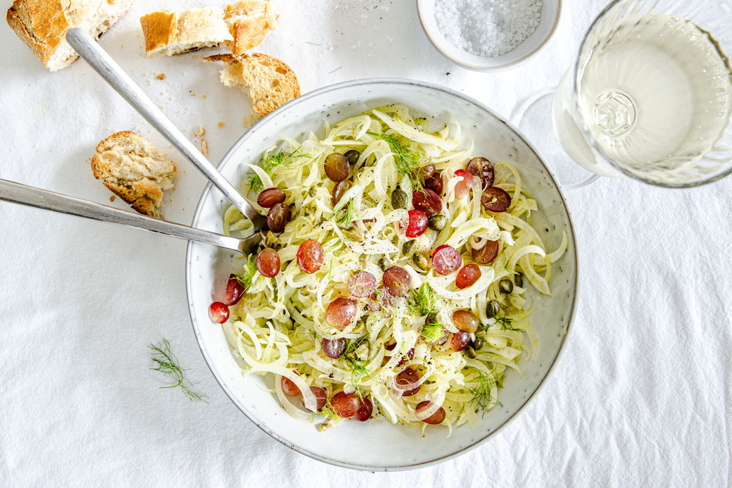 Frischer Fenchelsalat mit süßen Weintrauben, Kapern und Honig-Balsamico-Dressing auf rustikalem Teller serviert – leichtes Herbstgericht.