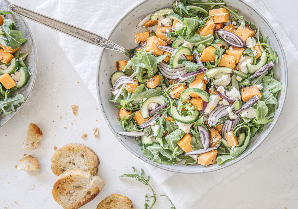 Herbstlicher Süßkartoffel-Rucola-Salat mit Feta und Balsamico-Dressing in einer Schüssel serviert