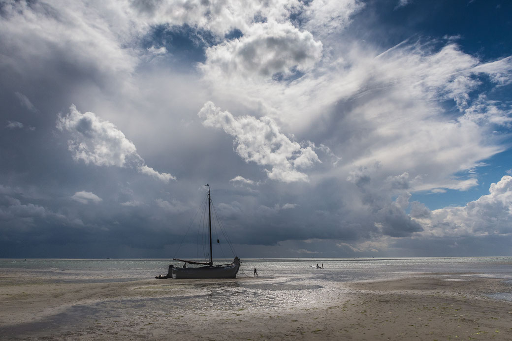 Drooggevallen zeilschip met op achtergrond een dreigende wolkenlucht boven de Noordsvaarder Terschelling