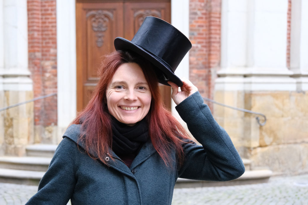 Frau mit Zylinder vor der Clemenskirche in Münster.
