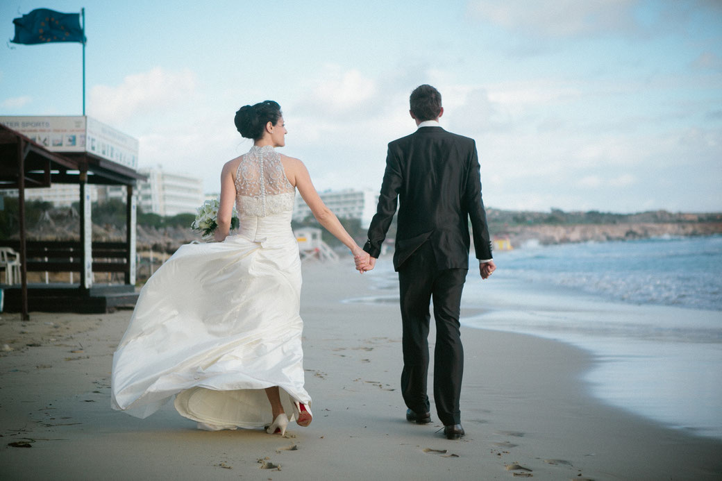 Natürliche Hochzeitsfotografie im Ausland – Brautpaar beim Spaziergang am Strand