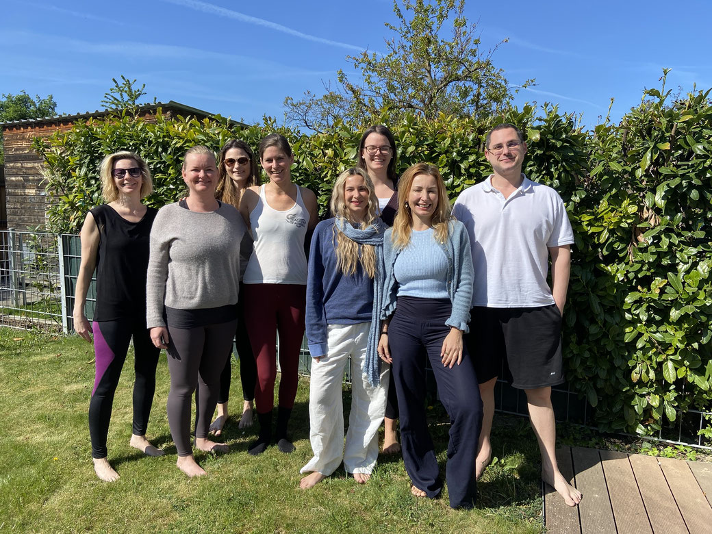 8 Yogis in der Sonne in der Wiese stehend