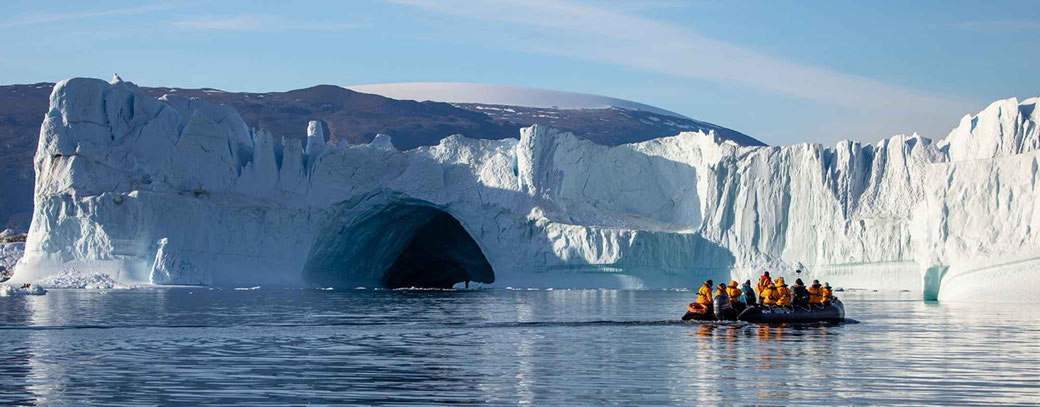 Menschen in einem Zodiacboot vor einem riesigen Gletscher in der Antarktis