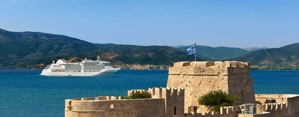 Kreuzfahrtschiff vor einer historischen Festung an der griechischen Küste mit Blick auf das tiefblaue Mittelmeer