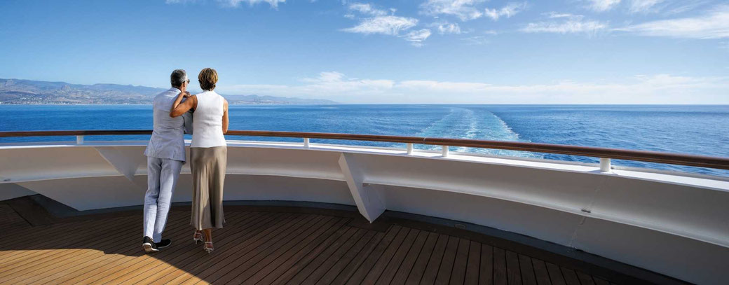 Ein Paar auf einem Regent Luxuskreuzfahrtschiff am Heck schaut auf das offene Meer.
