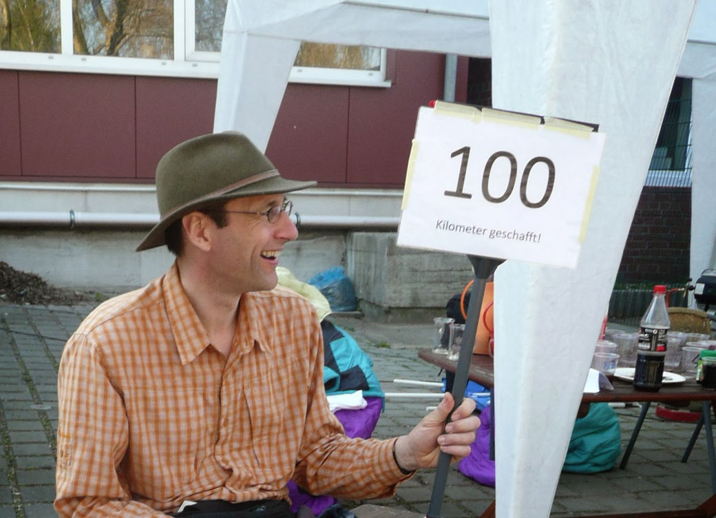 Martin glücklich mit einem Schild 100 km geschafft