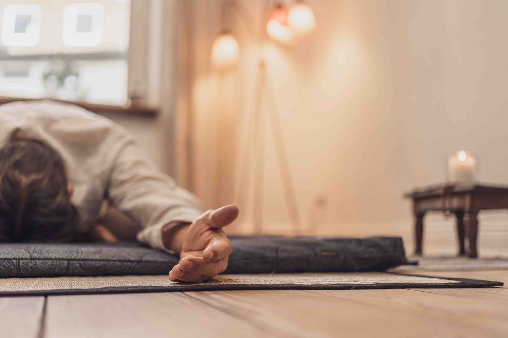 Martin liegt in einer entspannten Yogapose auf einem Futon