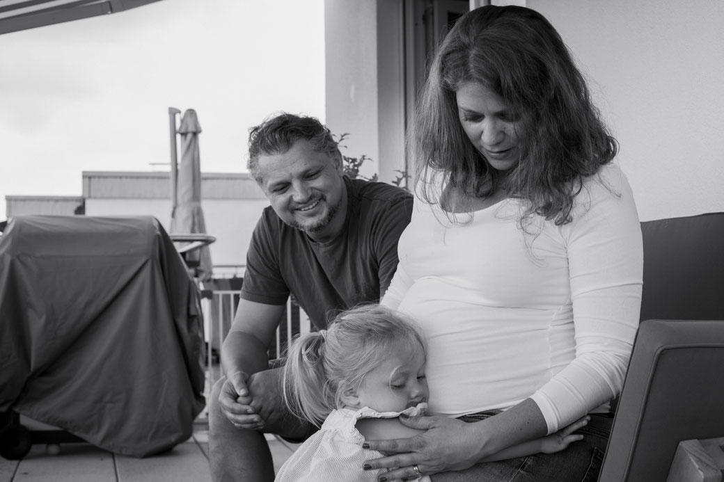 Als Hochzeitsfotograf Hanau beim Familienfotoshooting mit Babybauch in Offenbach. Die Tochter umarmt den Babybauch der Mutter.