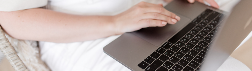 Frau sitzt auf dem Stuhl, arbeitet am Laptop.