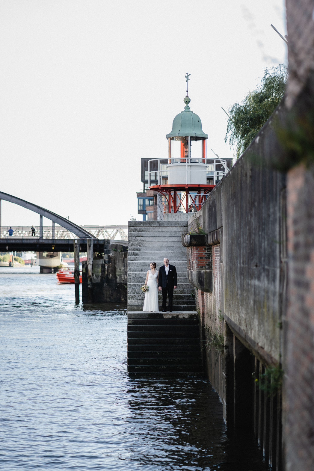 Brautpaar steht in der Hafencity auf einer Treppe runter zum Wasser. Eine Urbane Hochzeit in der Speicherstadt.