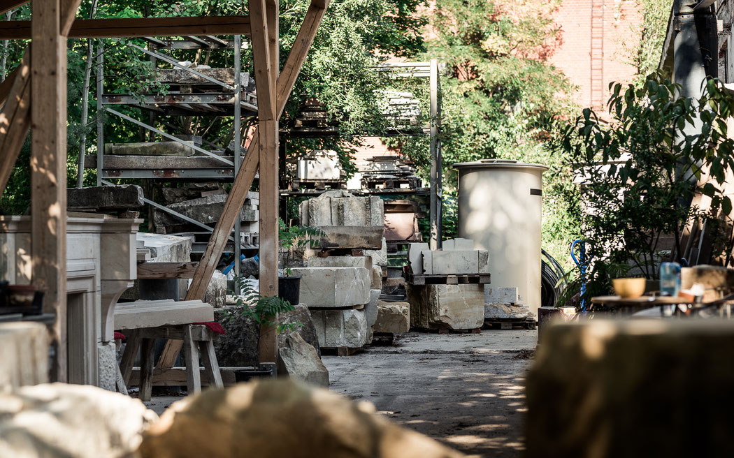 Das Außengelände der Meilenstein Werkstatt in Dresden: Sandstein Blöcke, ein Schauer zum Arbeiten und viele Pflanzen