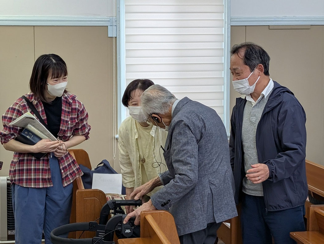 2026年5月3日(日)の礼拝後 白色のお洋服の方は今は関西にご家族で在住の旭東教会育ちの泉さん。右側の正さんに手を添えるのは泉さんのご主人さま。左のチェックのシャツの女性は泉さんと同じ時代に旭東教会の教会学校にご一家で通っていたよしみさんです。嬉しい再会の喜びの言葉を交わしている幸せな午後の時間帯でした。手前には、もう少したくさんのご家族の姿も見える姿があります。