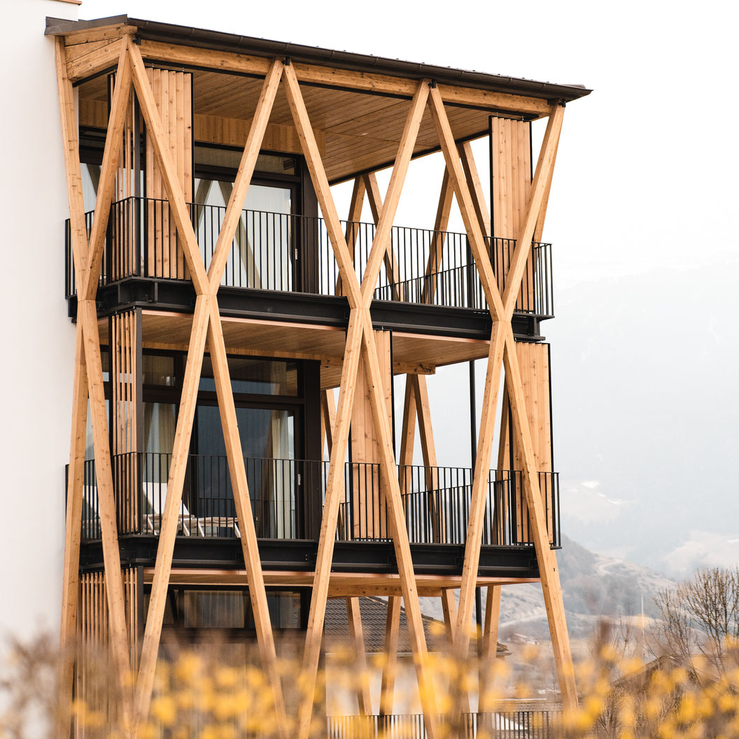 Die moderne Holzarchitektur des Garberhof mit markanten Balkonkonstruktionen und Blick in die alpine Landschaft.