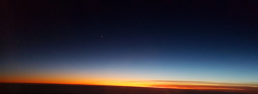 Sonnenuntergang mit Mondsichel (bei Vergrößerung über dem Horizont erkennbar) und Sternen (Planeten?), aufgenommen am 27.12.2019 aus dem Flugzeug