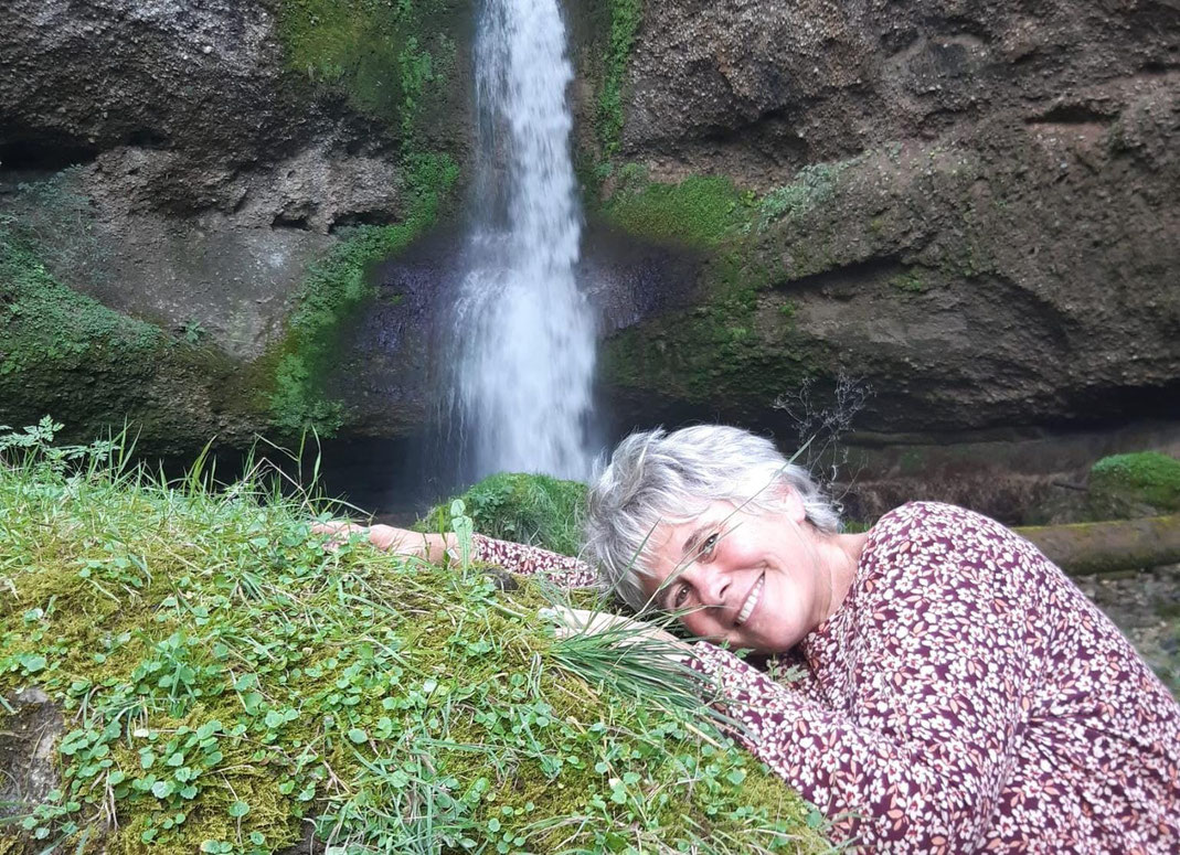 Ich liege auf einem Moosbewachsenen Stein, im Hintergrund ein Wasserfall.
