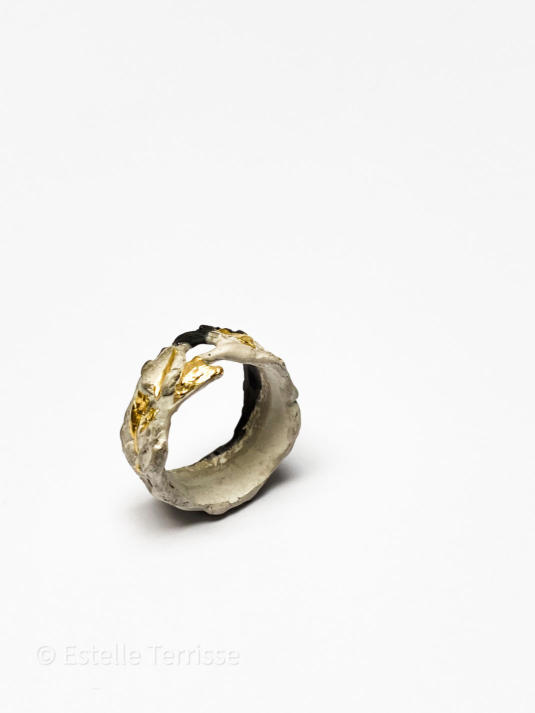 cette bague irrégulière est de couleur blanche, noire. Des touches d'or la parsèment d'ici, de là.