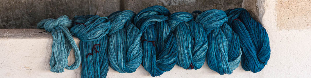 Fils de coton teints dans différentes nuances de bleu, du bleu turquoise au bleu foncé. Dans l'étape suivante, ces fils seront tissés pour confectionner des tissus.
