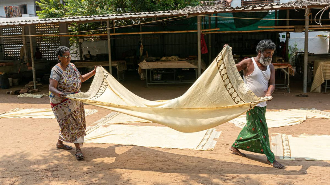 Tissu partiellement imprimé, étalé à même le sol sous le soleil, afin d’achever le séchage de la teinte brune tout juste appliquée.