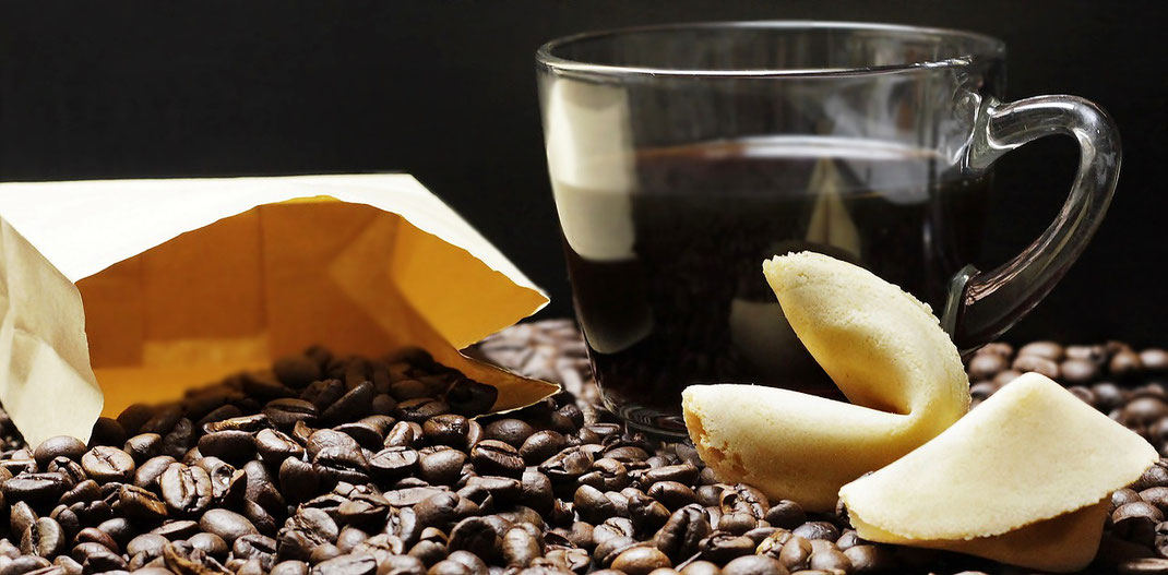 Bild mit einer Tasse Kaffee, Kaffeebohnen und zwei Glückskeksen