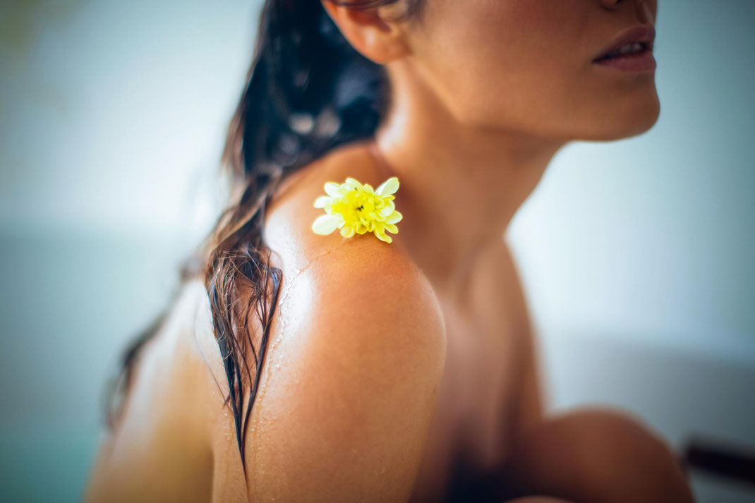 Eine Blüte auf einer nackten Frauenschulter als Symbolbild für Rückenthemen