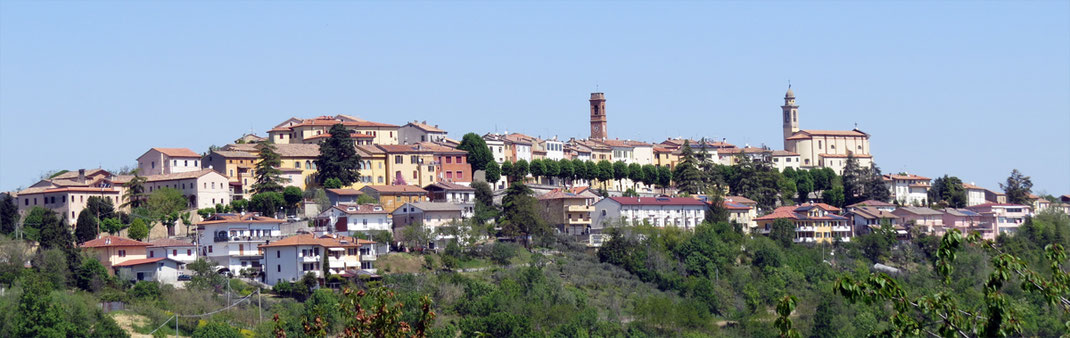 Sehenswürdigkeiten in der Umgebung von San Marino: Die in sanften Farben bemalten Häuser von Sogliano al Rubinaco wurden eng aneinander gebaut, auf dem höchsten Punkt eines der Hügel. 