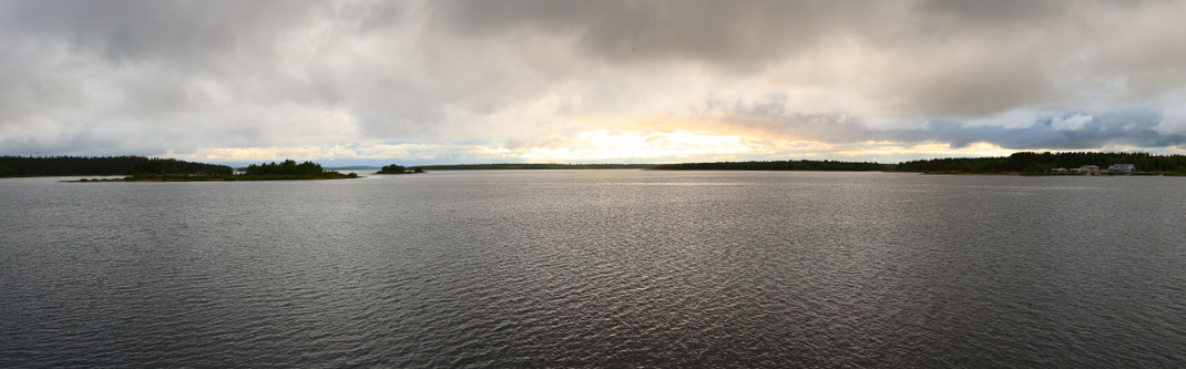 Sehenswürdigkeiten Finnland: Die tief stehende Mittsommernachtssonne scheint über die ruhige Wasseroberfläche des Porttipahta-Stausees.