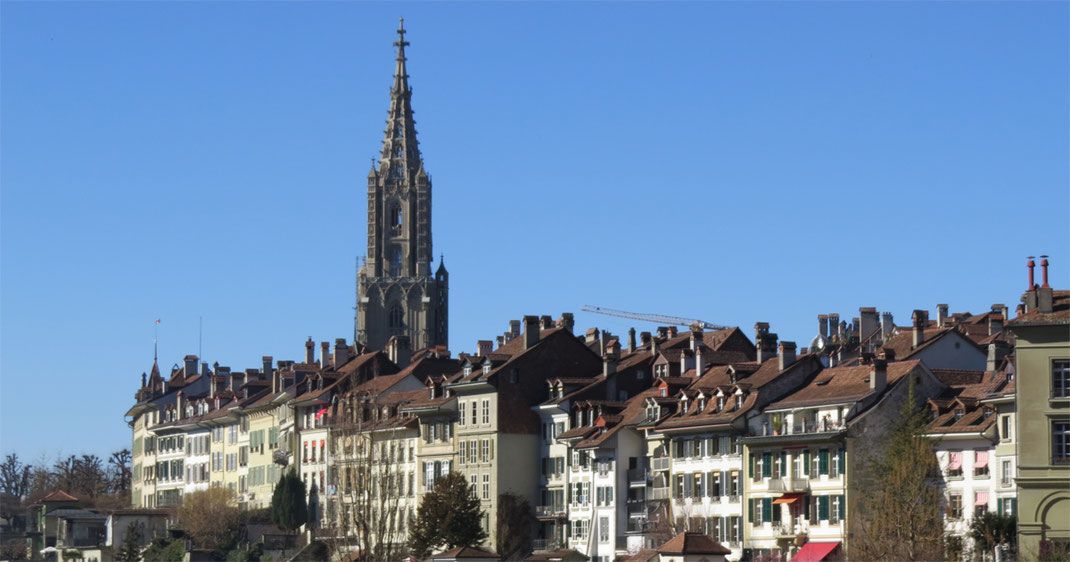 Sehenswürdigkeiten Bern: Altstadt und Berner Münster vom gegenüberliegenden Aareufer betrachtet.