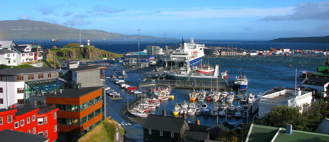 Sehenswürdigkeiten Tórshavn: Die Freizeitboote und die großen Fähren liegen in der Ostbucht, unmittelbar neben der Hügelfestung «Skansin» mit dem weiß-roten Leuchtturm.