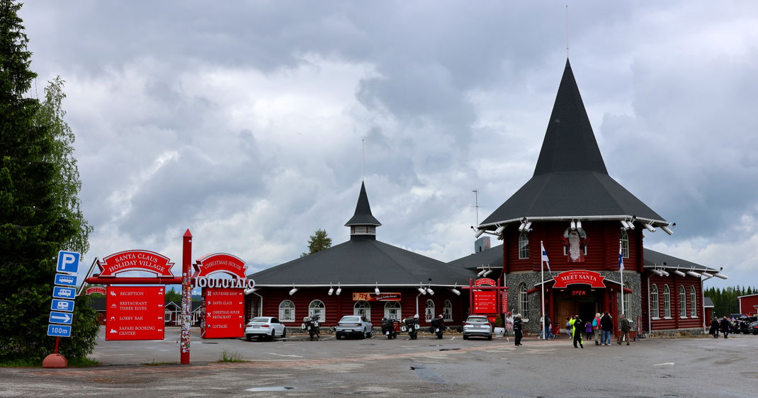 Sehenswürdigkeiten Rovaniemi: Zwei der Gebäude des Weihnachtsmanndorfs von Rovaniemi. Im Innern befinden sich Geschenk- und Souvenirläden, wie man sie aus den USA her kennt: Bis in den hintersten Ecken überfüllt, in grellen Farben und hell beleuchtet.