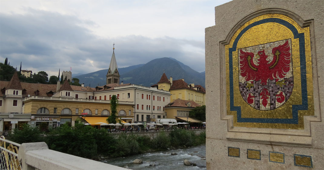 Sehenswürdigkeiten Meran: Postbrücke über die Passer mit Wappen von Meran und dem Turm der Herz-Jesu-Kirche.